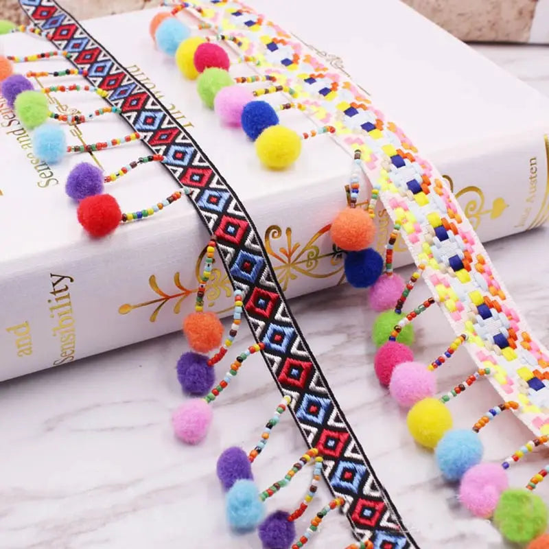 Colorful mini pom pom fringe lace trim with various colors like yellow, pink, and blue on a white background.