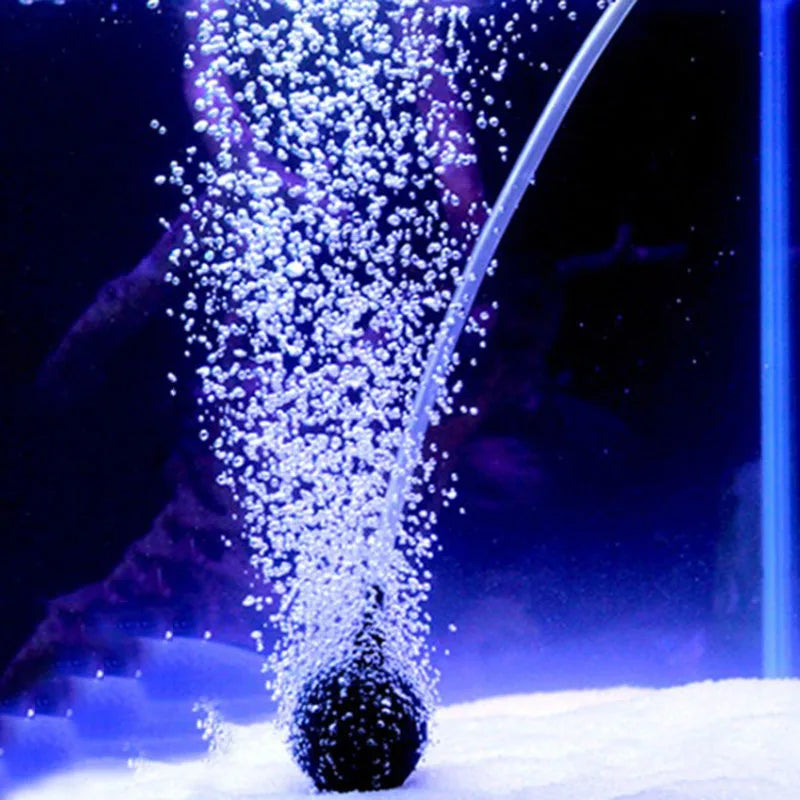 A stream of water sprays into a pool of white snow, creating fine droplets and mist.