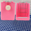 Étalage de foin pour lapin rose avec cage en filet et conteneur rose solide sur surface à grille bleue.