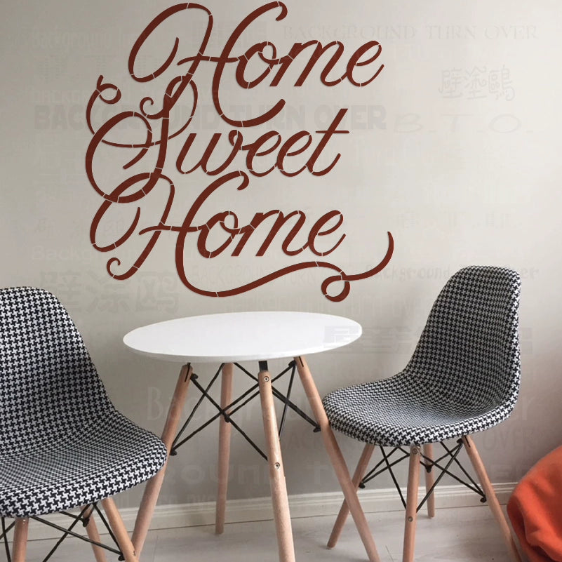 Pochoir mural avec la phrase Home Sweet Home en écriture calligraphique marron, affiché au-dessus d'une table blanche avec de