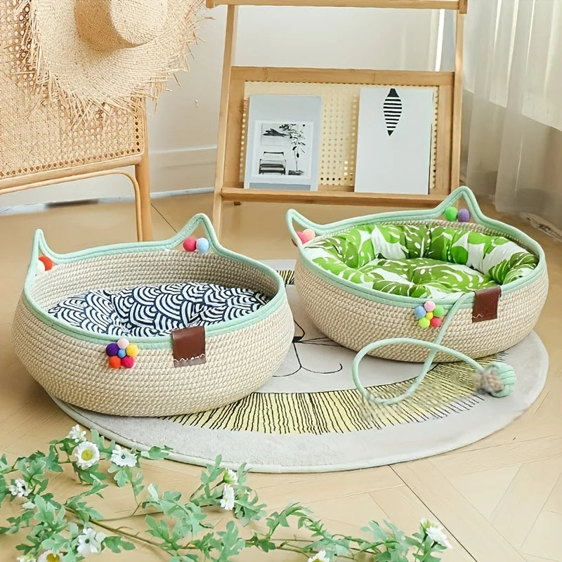 A beige hand woven rattan cat bed with a scratching surface and green and white fabric lining sits on a light wooden floor.