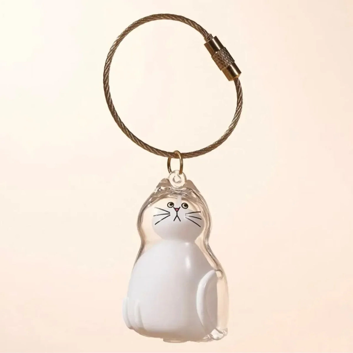 A clear glass figurine of a white cat is suspended from a braided leather keychain.