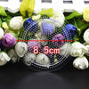A clear plastic dish filled with various colored and textured beads surrounded by fresh flowers.