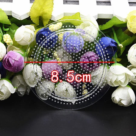 A clear plastic dish filled with various colored and textured beads surrounded by fresh flowers.