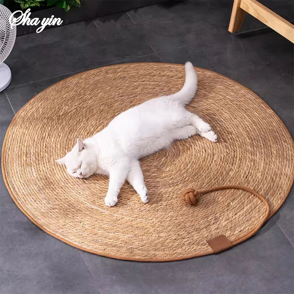 A white cat is lying on a round natural rattan mat, using a wooden cat scratcher tool.