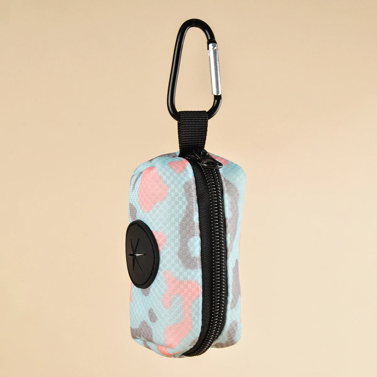 A small, zippered poop bag dispenser featuring a light blue and pink camouflage pattern with a black clip.