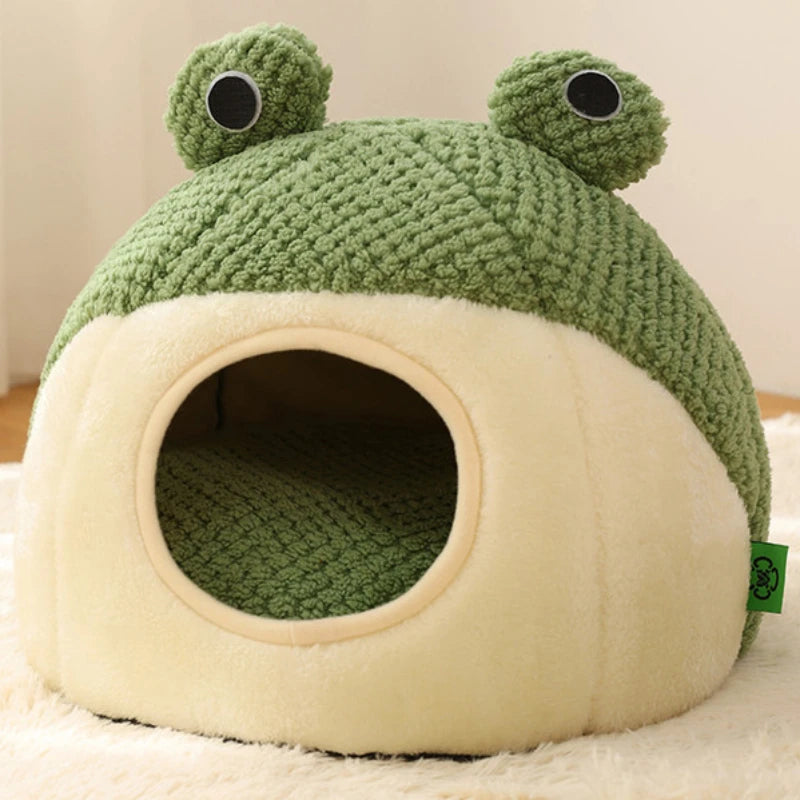 Un nido de mascota de peluche verde con grandes ojos sentado sobre una base crema antideslizante.