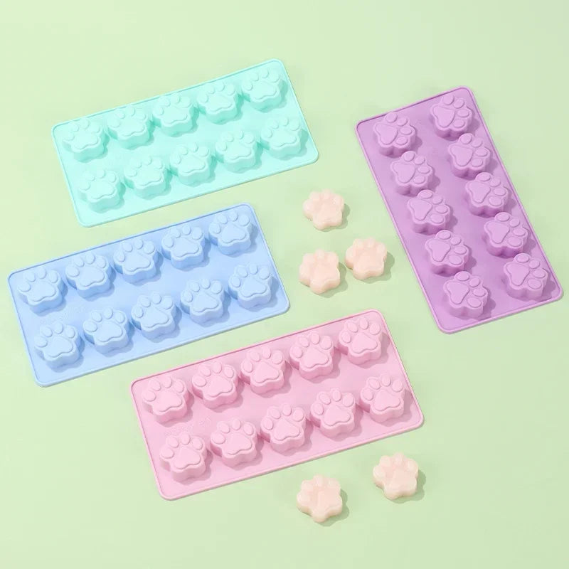 A set of silicone dog paw and bone treat molds in various shades of purple, blue, and pink.