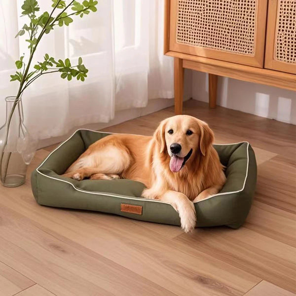 A golden retriever dog is lying on a green square dog bed indoors.