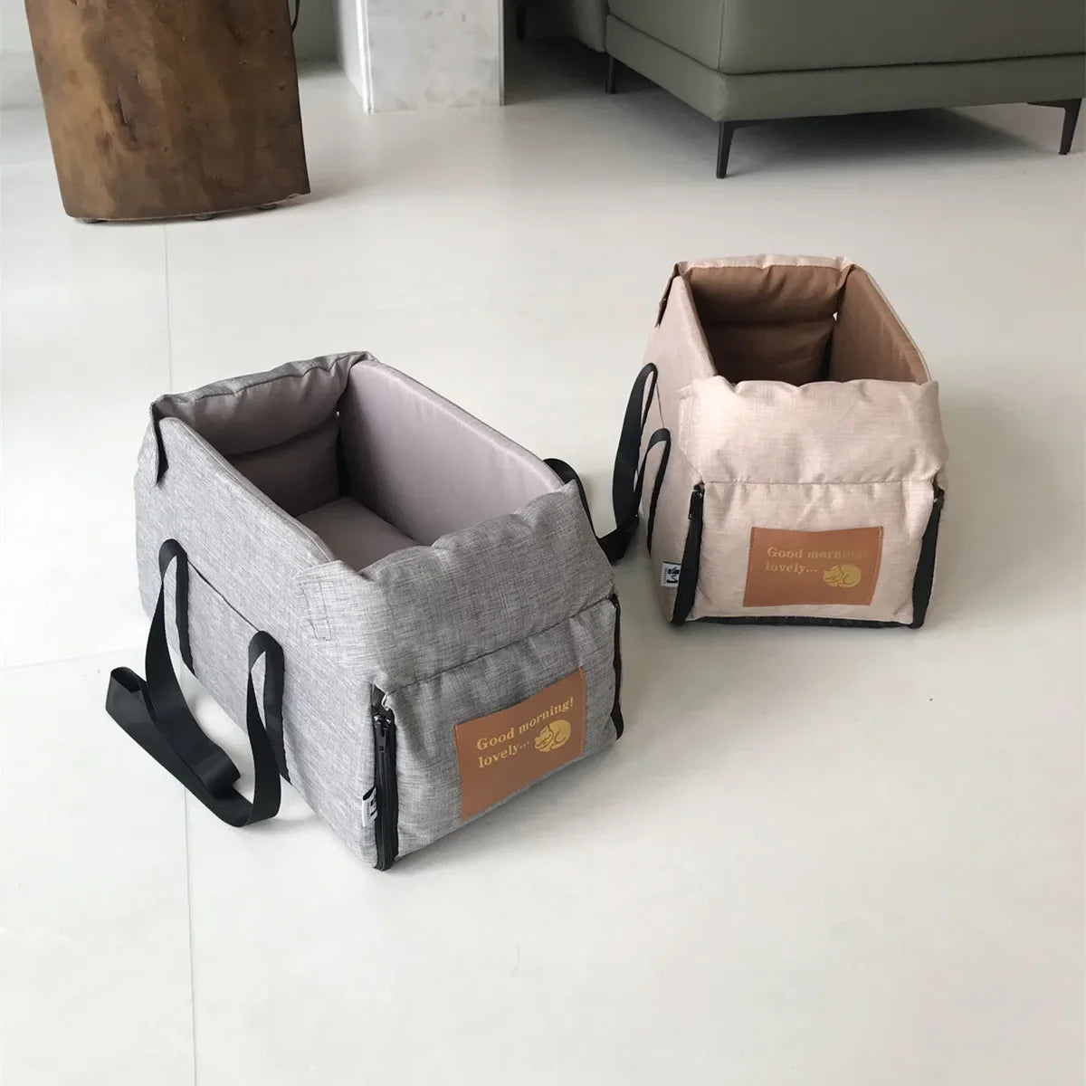 Two beige fabric pet carriers are displayed on a white floor.