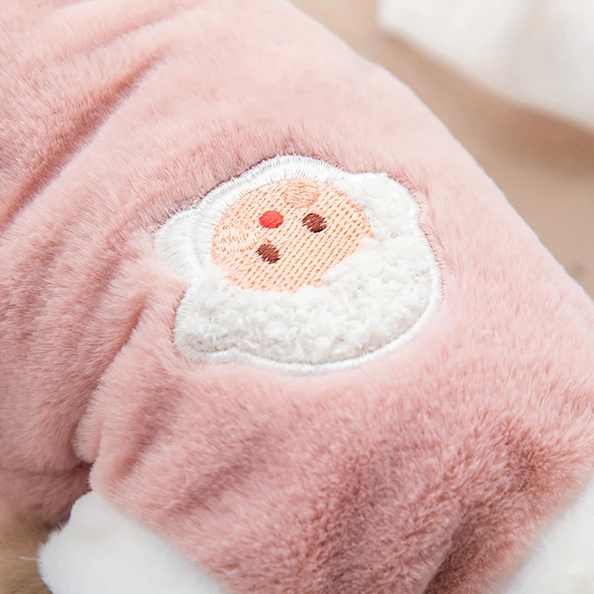 A soft pink fuzzy pet vest embroidered with a white, fluffy beard and eyes.