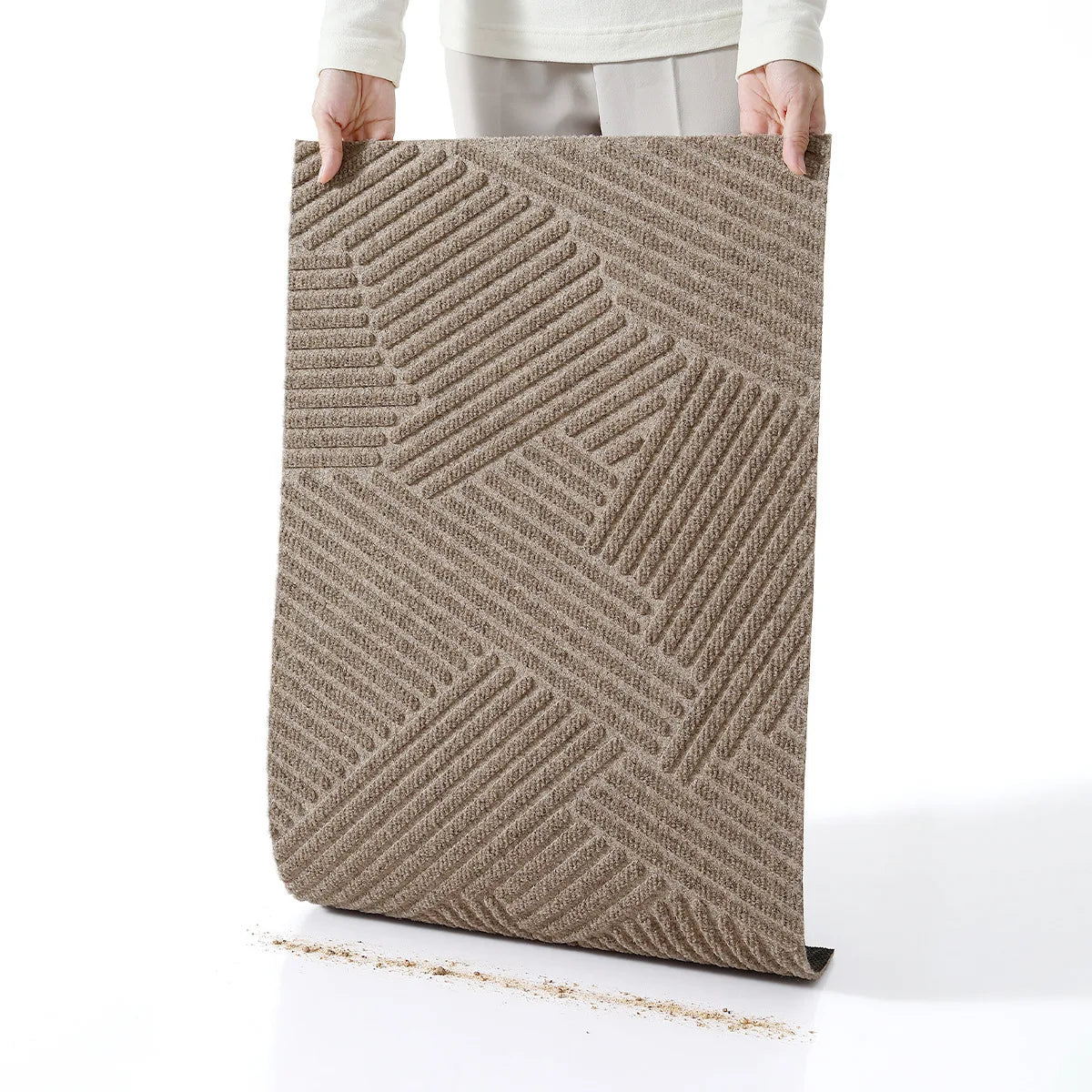 A rectangular brown geometric non-slip doormat is held by a person, showing its textured surface.