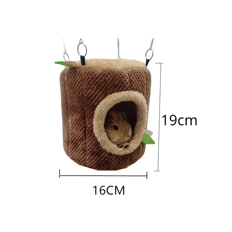 Cama de nido cilíndrica marrón para hámster, con orificio de entrada y pequeñas hojas verdes.