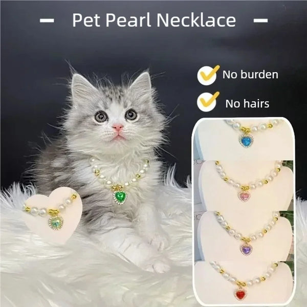 A fluffy gray kitten wearing a delicate pearl necklace with a green pendant.