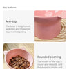A pink pet feeding bowl with a rounded opening and an anti-slip base, filled with dry pet food.
