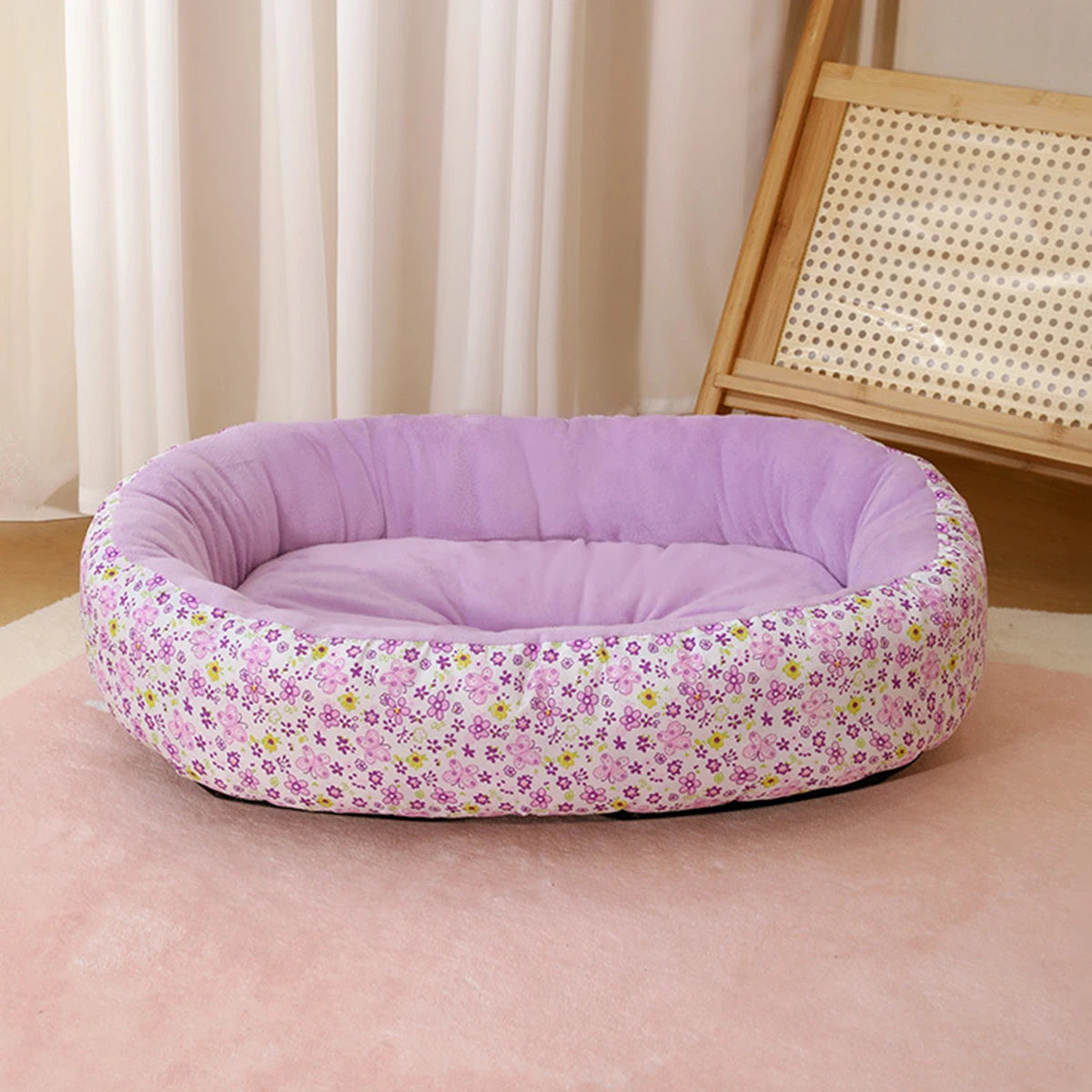A purple floral pet bed for small dogs and cats resting on a pink carpet.