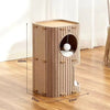 A light brown wooden cat house with a circular entrance and a fluffy ball inside, shown on a wooden floor.