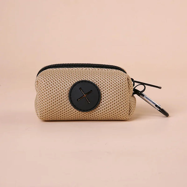 A beige canvas poop bag dispenser with a black circular detail and a carabiner clip.