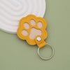 A yellow leather paw print keepsake with a silicone pad attached to a silver keyring.