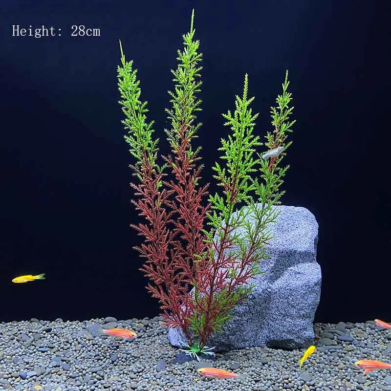 A tall artificial aquarium plant with reddish-brown and green foliage is displayed on a gray rock amidst small pebbles.