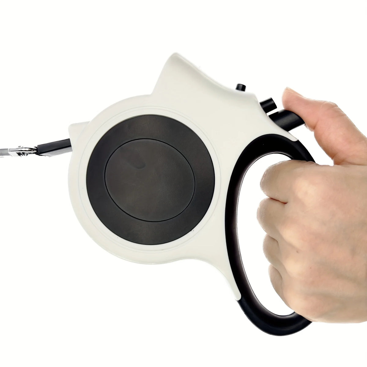 A hand is holding an illuminated retractable dog leash with a white and black body and silver tip.