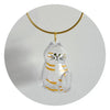 A clear glass pendant shaped like a striped cat is suspended from a gold-colored chain.