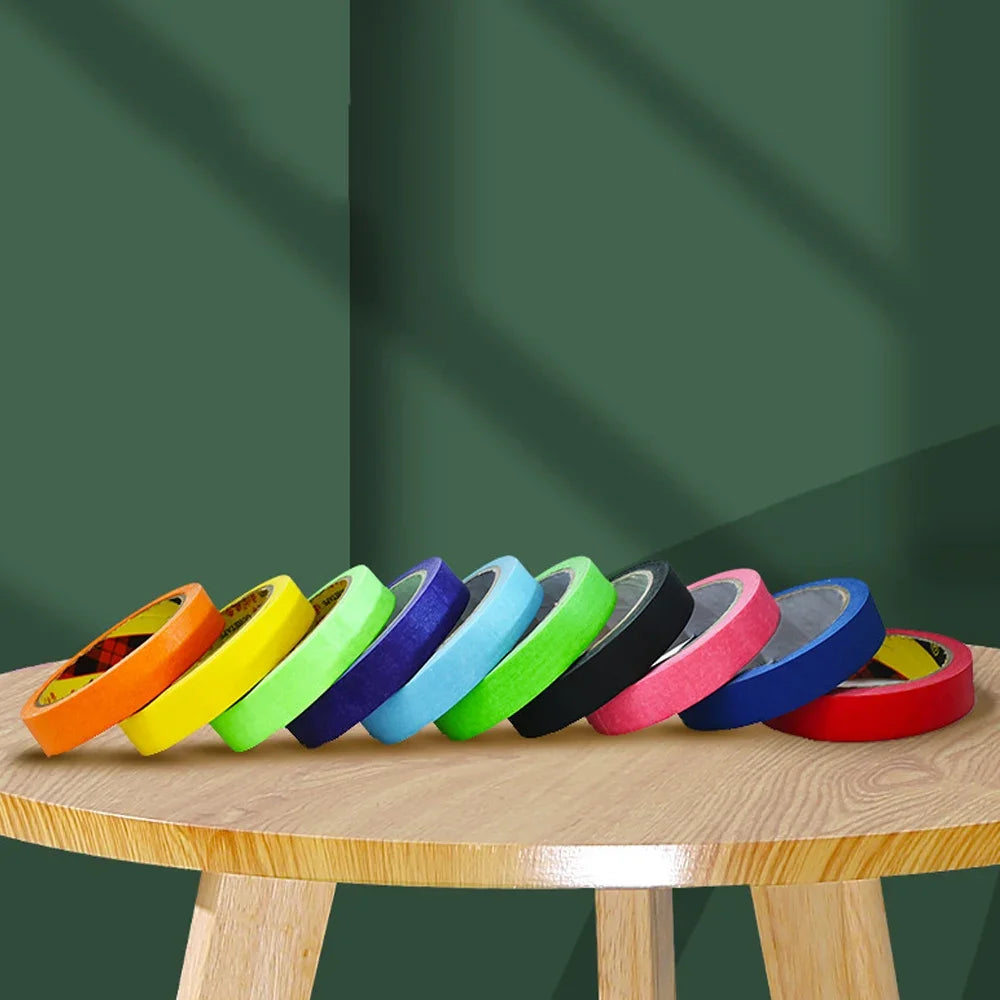 A collection of colorful orange multi-surface masking tape rolls laid out on a wooden surface.