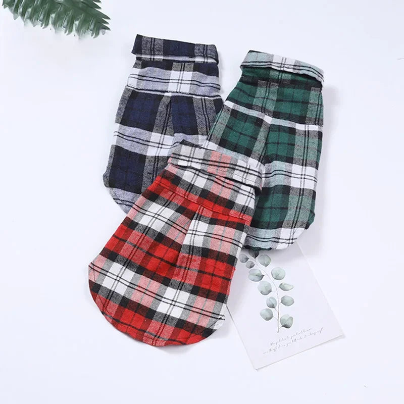Three folded British plaid dog vests in red, green, and blue patterns.