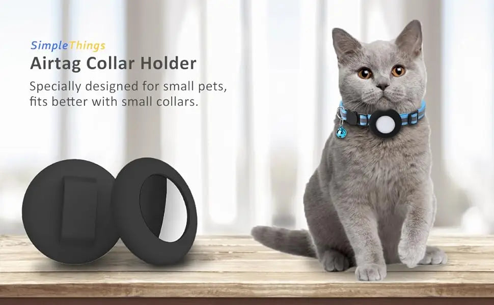 A gray cat sitting on a wooden surface next to a black silicone AirTag collar holder.