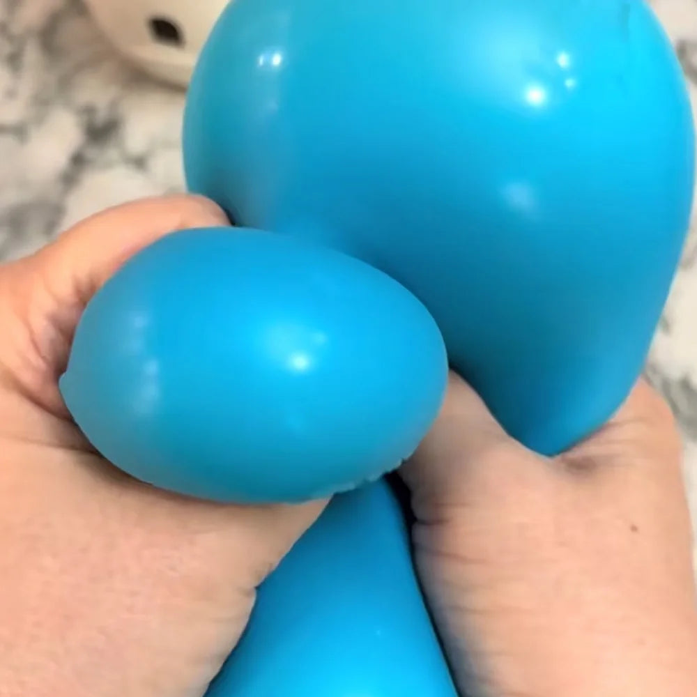 A hand is squeezing a bright blue, oval-shaped stress ball toy.