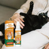 A bottle of Yegbong Cat Deterrent Spray is held by a person, with a black cat resting nearby.