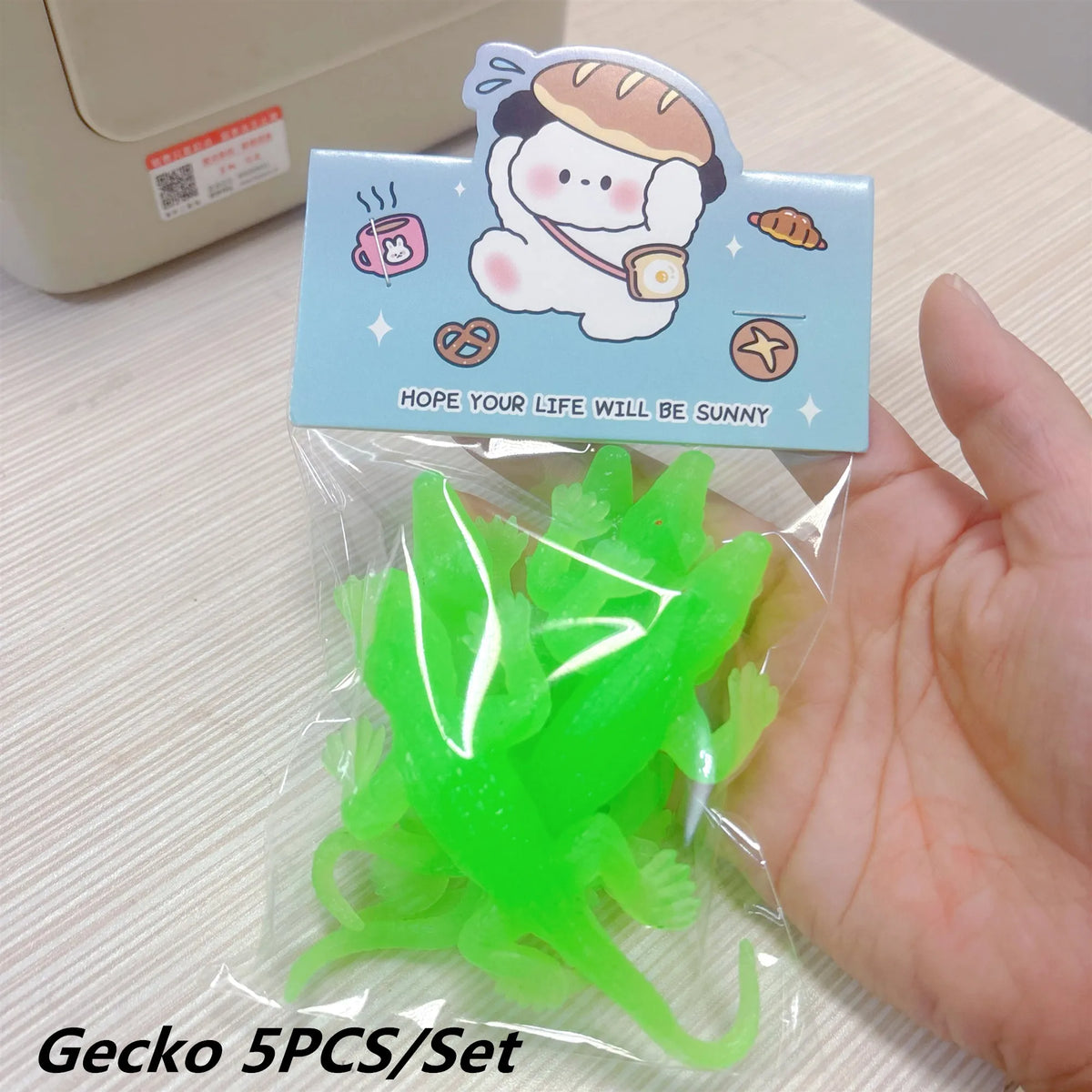 A clear plastic bag contains five bright green soft rubber gecko bath toys with a decorative cardboard backing.