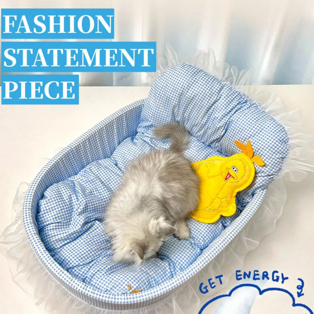 A fluffy gray kitten is resting inside a blue and white pet sofa bed with a yellow toy.