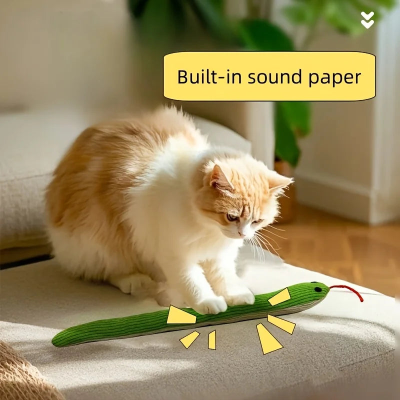 A fluffy orange and white cat is playing with a green crinkle toy.