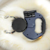 A dark blue retractable dog leash with an LED light is displayed on a white, fluffy surface.