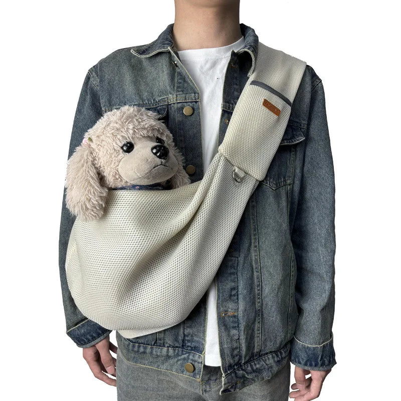 A person wearing a denim jacket and white shirt with a beige breathable mesh dog carrier crossbody bag.