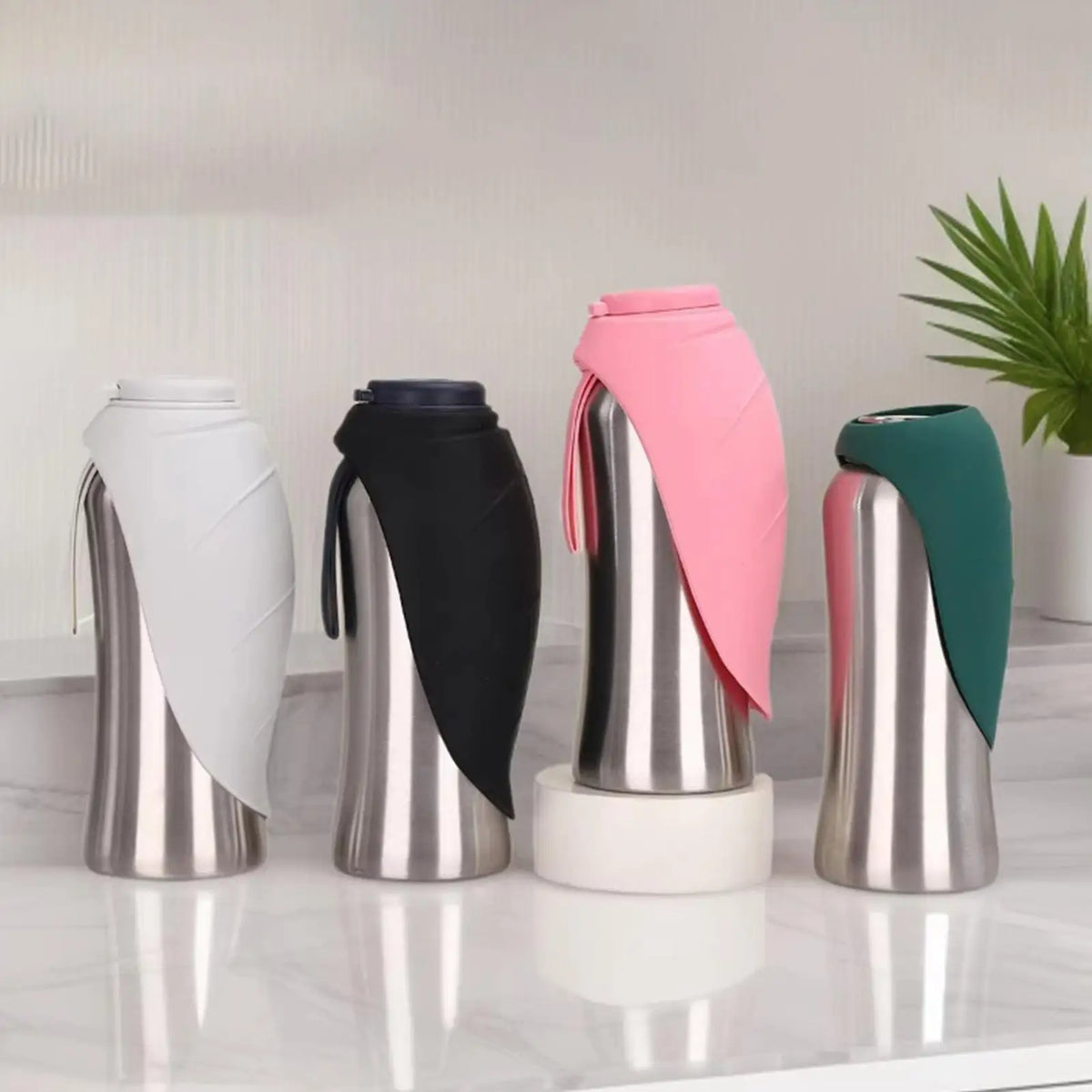 A set of portable leak-proof dog water bottles with built-in bowls in silver, black, and pink.