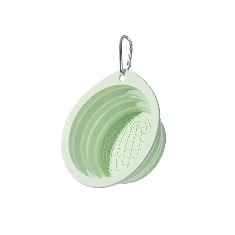 A light green collapsible silicone pet travel bowl with a metal hanging loop.