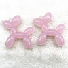 Two pink acrylic balloon dog charm pendants displayed on a white, fuzzy surface.