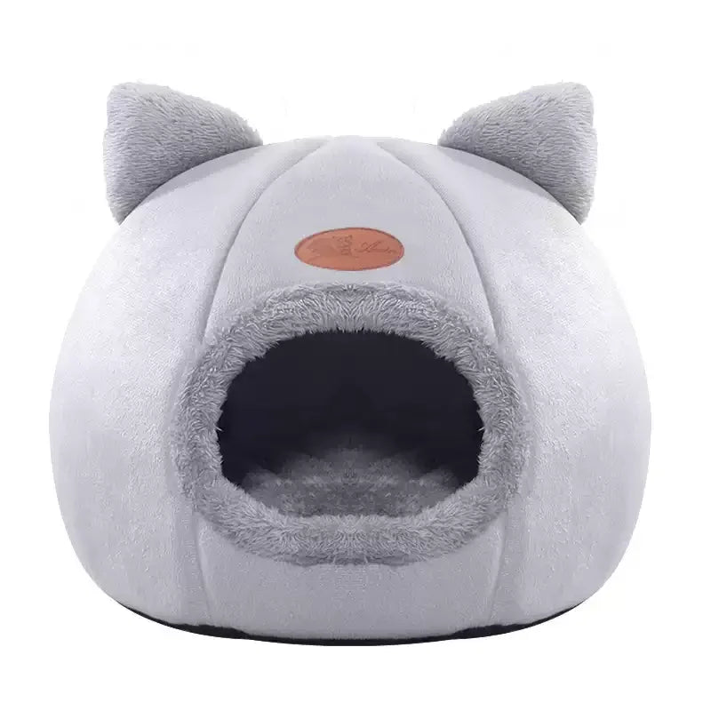 Un lit pour chat en peluche gris avec des oreilles arrondies et un trou d'entrée.