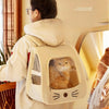 Eine Person trägt einen beigen, faltbaren Hundetransporter-Rucksack mit einer transparenten Öffnung, in der eine Katze steckt