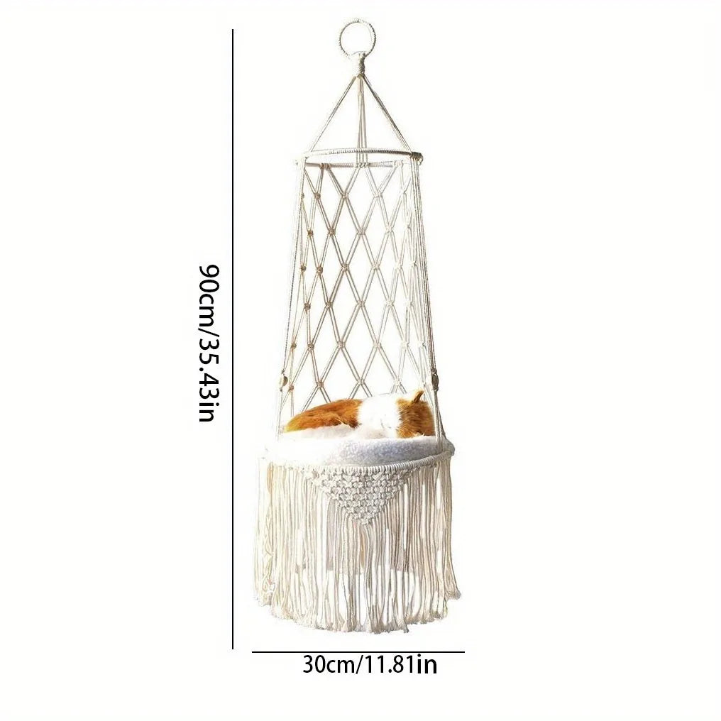 A hanging cat hammock bed made of white twine and netting for a window or balcony.