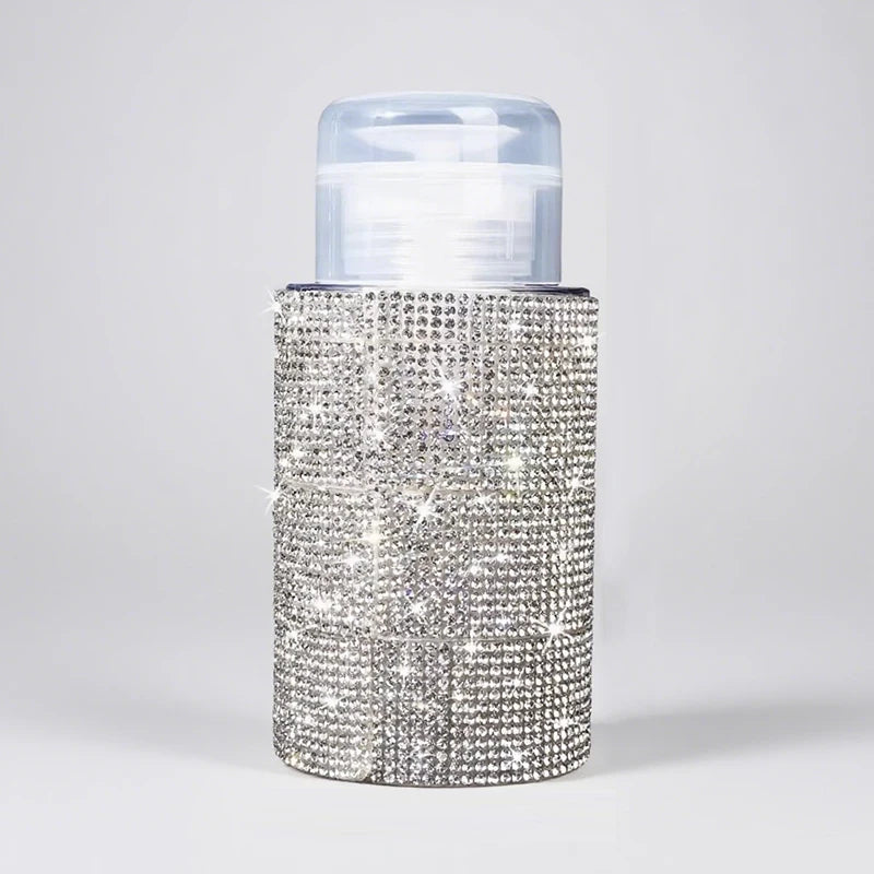 A clear pump bottle with a silver diamond-encrusted exterior and a translucent cap.