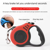 An orange and black automatic retractable dog leash is shown with a hand demonstrating its use.