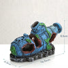 A blue aquarium ornament shaped like a sunken ship with a cave hideout, featuring green moss details.