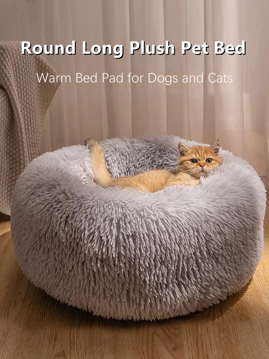 A round, long gray plush pet bed with a cat resting inside on a wooden floor.