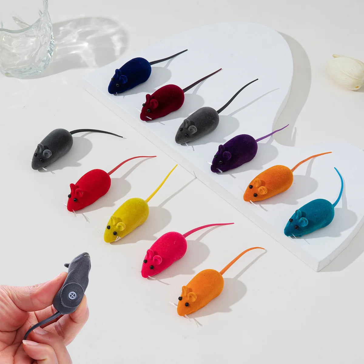 A collection of colorful squeaking mouse toys for cats arranged on a white surface.