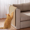 An orange cat is interacting with a sisal scratching board placed next to a beige sofa.