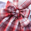 A plaid red and white fabric bow detail on a reusable dog harness dress.