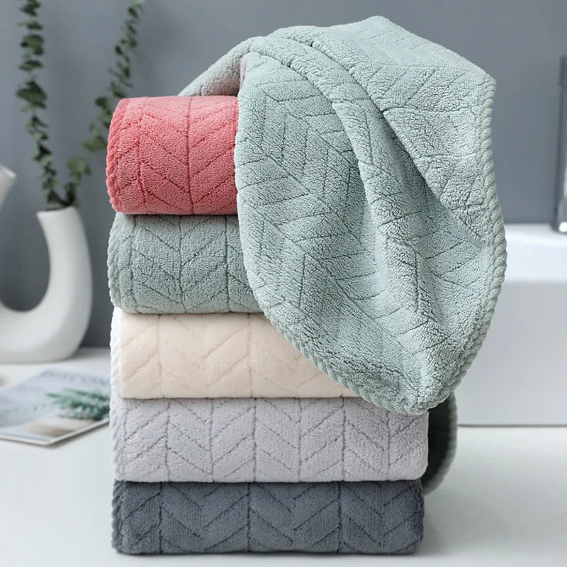 A stack of folded gray and pink microfiber bath towels on a white surface.